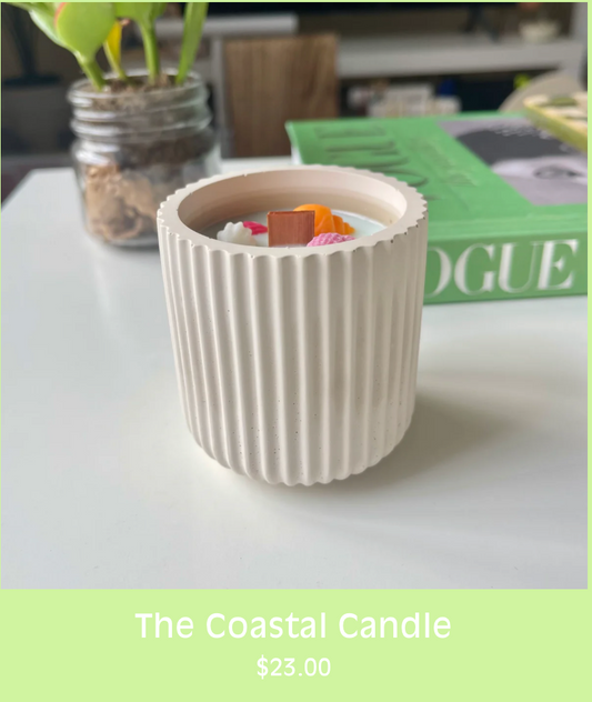 a small coastal concrete candle with colorful wax seashells