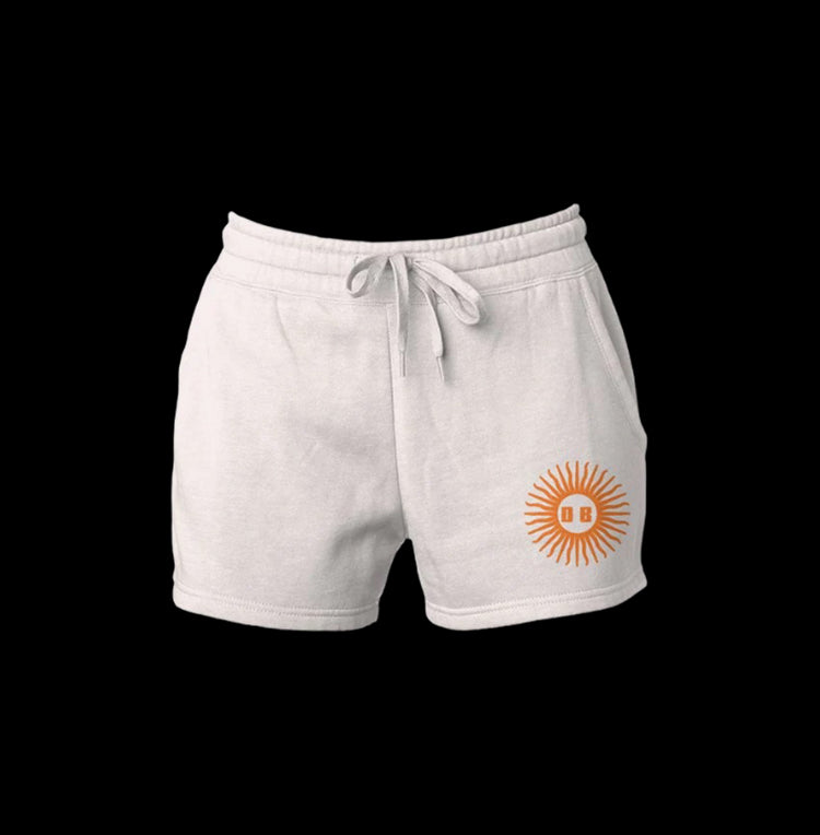 Neutral tan cotton shorts with embroidered sun design on leg.